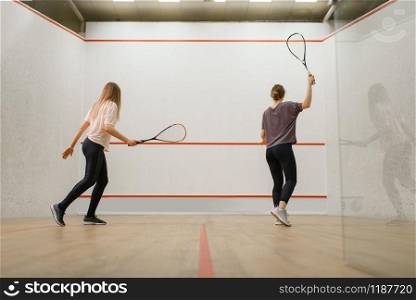 Two female players with rackets, squash game on court. Girls on training, active sport hobby, fitness workout. Two female players with rackets, squash game