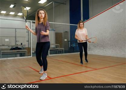 Two female players with squash racket playing on court. Girl on game training, active sport hobby, fitness workout for healthy lifestyle. Two players with squash racket playing on court