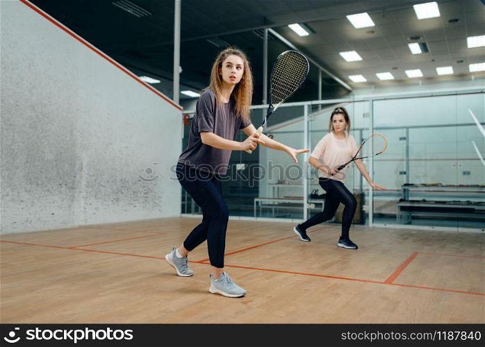 Two female players with squash racket playing on court. Girl on game training, active sport hobby, fitness workout for healthy lifestyle. Two players with squash racket playing on court