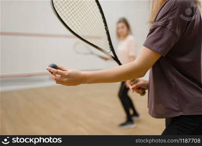 Two female players with squash rackets, focus on ball. Girls on training, active sport hobby, fitness workout for healthy lifestyle. Female players with squash rackets, focus on ball