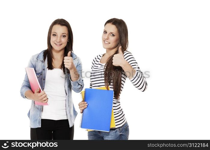 two female students showing thumbs up. two female students with exercising books showing thumbs up on white background