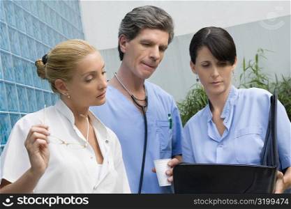 Two female surgeons and a male doctor discussing a medical report