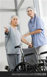 Two female surgeons standing near a wheelchair