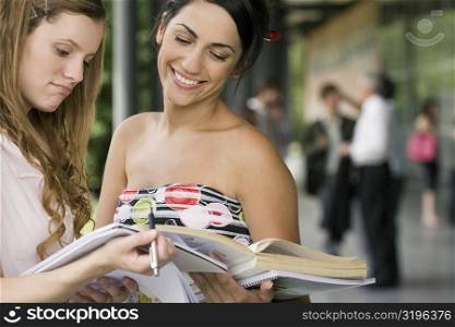 Two female university students discussing in a corridor