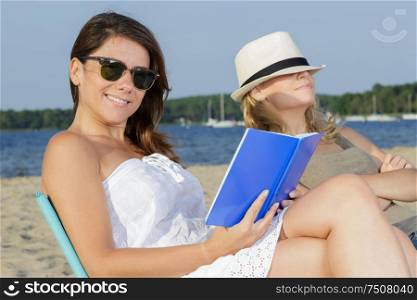 two female young adults reading books on beach