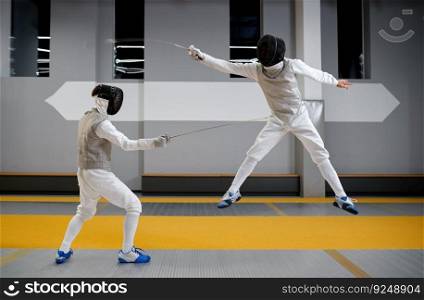 Two fencers sparring during training session in professional martial art school. Swordsman jumping trying to dodge an attack. Two fencers sparring during training session in professional martial art school