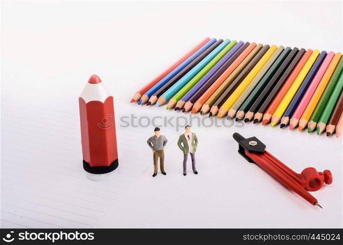 Two figurine standing by pen, pencils, compass