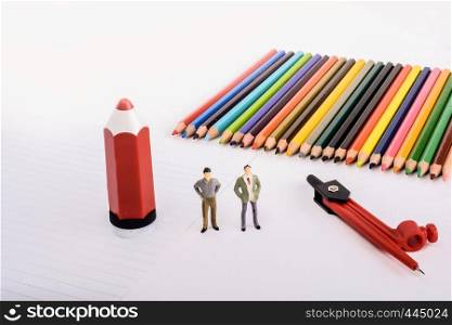 Two figurine standing by pen, pencils, compass