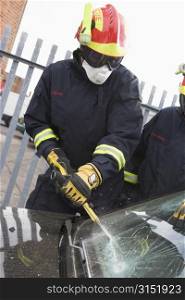 Two firefighters cutting out a windshield after an accident
