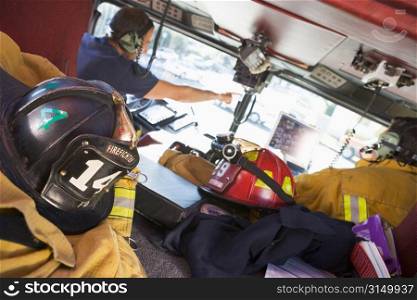 Two firefighters driving a fire engine with gear in the back (selective focus)