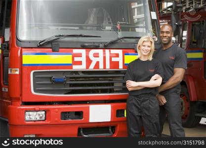 Two firefighters standing in front of fire engine