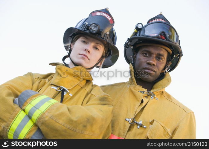 Two firefighters standing outdoors wearing helmets