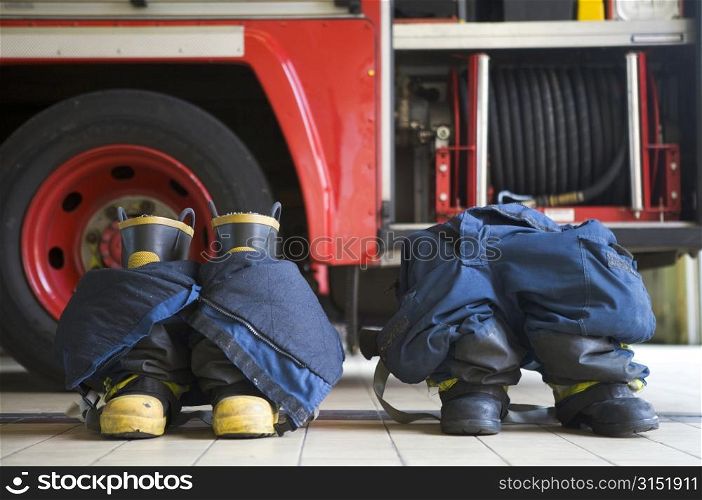 Two firefighting uniforms on floor by fire engine
