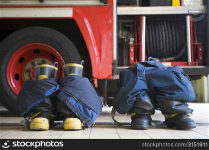 Two firefighting uniforms on floor by fire engine
