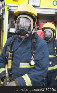 Two firemen in masks standing near fire engine (depth of field)