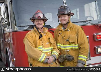 Two firemen standing in front of fire engine