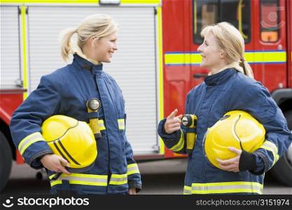 Two firewomen standing by fire engine talking