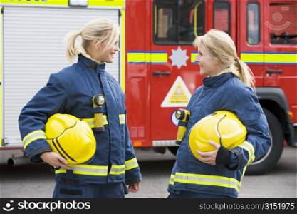 Two firewomen standing by fire engine talking