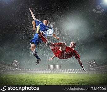 two football players in jump to strike the ball at the stadium