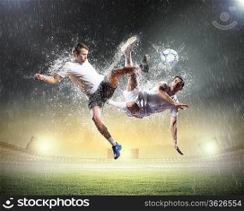 two football players in jump to strike the ball at the stadium