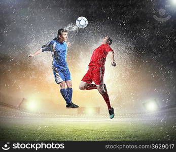 two football players in jump to strike the ball at the stadium