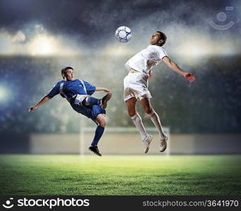 two football players in jump to strike the ball at the stadium