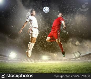 two football players striking the ball. two football players in jump to strike the ball at the stadium