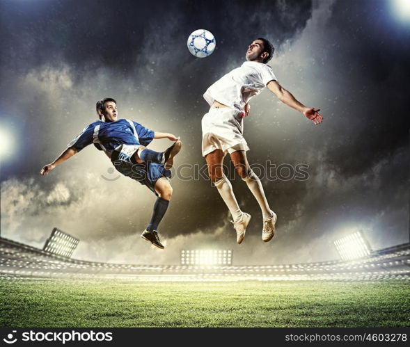 two football players striking the ball. two football players in jump to strike the ball at the stadium