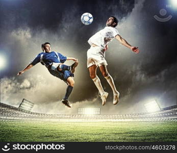 two football players striking the ball. two football players in jump to strike the ball at the stadium