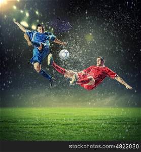 two football players striking the ball. two football players in jump to strike the ball at the stadium