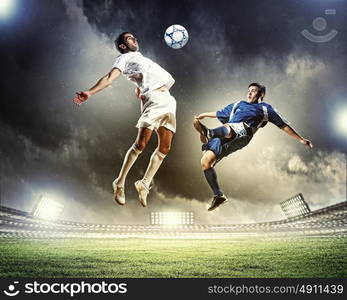 two football players striking the ball. two football players in jump to strike the ball at the stadium