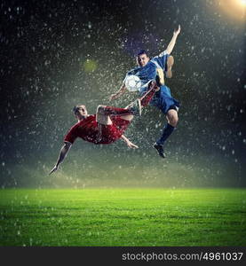 two football players striking the ball. two football players in jump to strike the ball at the stadium