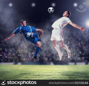 two football players striking the ball. two football players in jump to strike the ball at the stadium