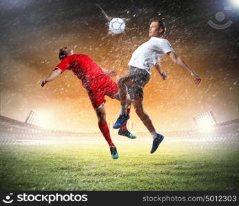 two football players striking the ball. two football players in jump to strike the ball at the stadium