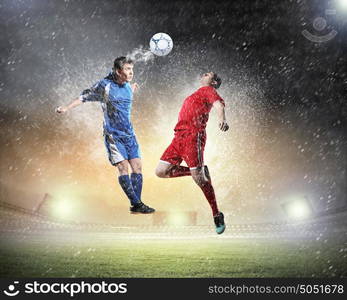 two football players striking the ball. two football players in jump to strike the ball at the stadium