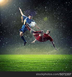 two football players striking the ball. two football players in jump to strike the ball at the stadium