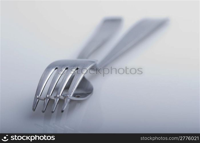 Two forks one over another overe white background