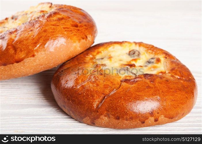 Two fresh homemade buns with cottage cheese and raisins on a wooden table