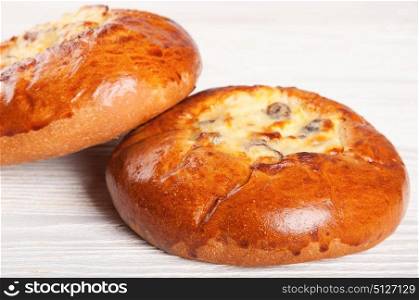 Two fresh homemade buns with cottage cheese and raisins on a wooden table