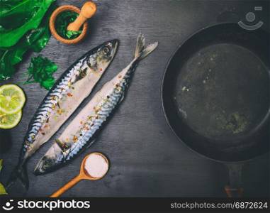 Two fresh mackerels in spices for cooking in a frying pan, top view