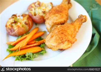 Two fried chicken legs with smashed potatoes and carrots