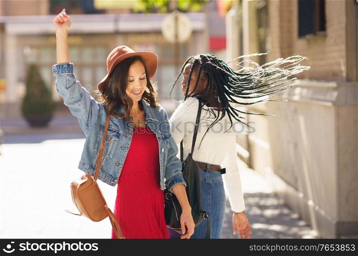 Two friends dancing together on the street. Multiethnic women.. Two female dancing together on the street. Multiethnic friends.