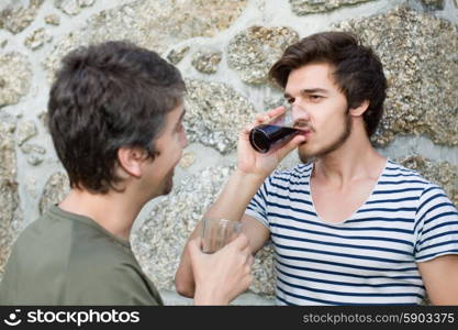 two friends having a drink and talking outdoors