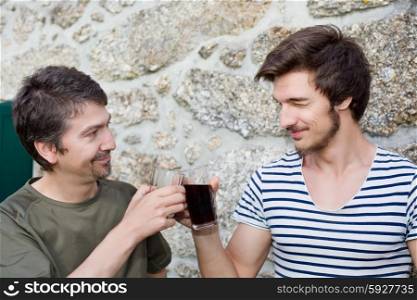 two friends having a drink and talking outdoors, focus on the man on the right