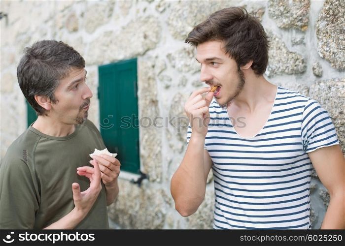 two friends having a snack and talking outdoors