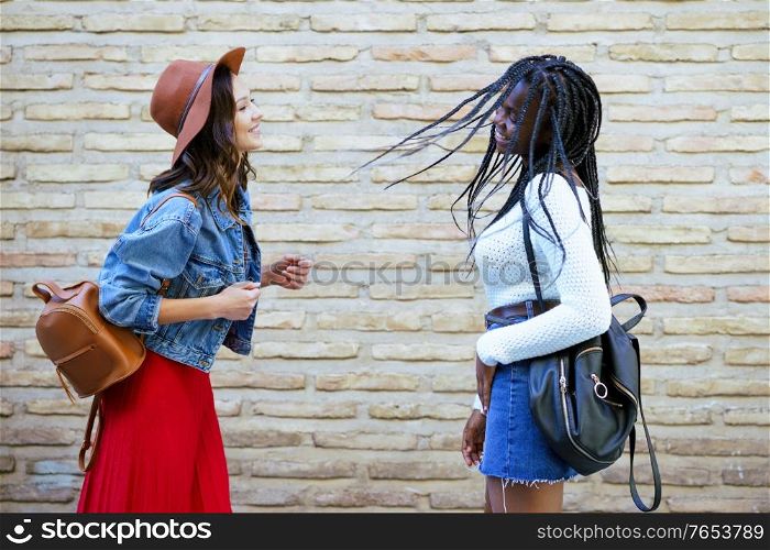 Two friends having fun together on the street. Multiethnic women.. Two female friends having fun together on the street. Multiethnic friends.