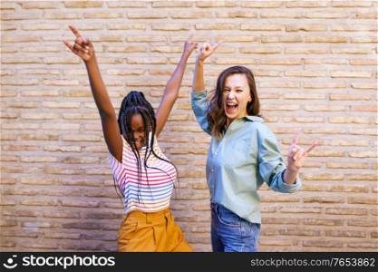 Two friends having fun together on the street. Multiethnic women.. Two female friends having fun together on the street. Multiethnic friends.