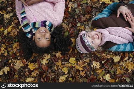 Two friends lying on autumn leaves
