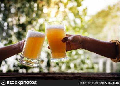 Two Friends making Cheers with Glasses and Drinking Beer at the Balcony in Summer