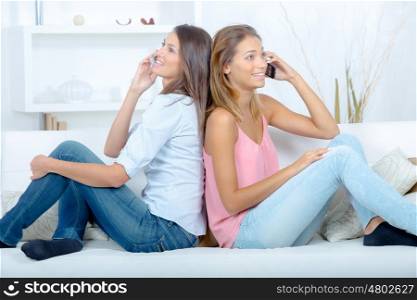 two friends on a sofa using their mobile phone